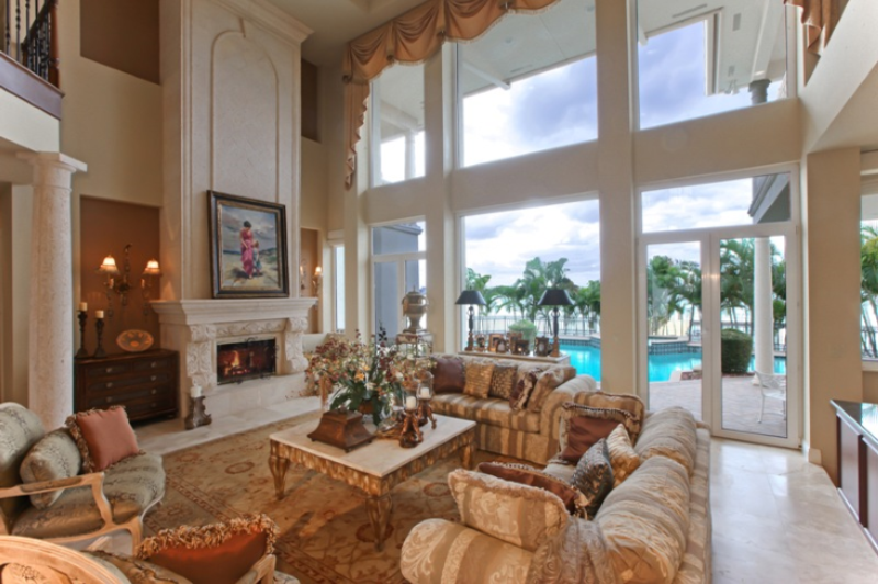 bright Florida living room, high ceilings, tall windows, view of turquoise swimming pool